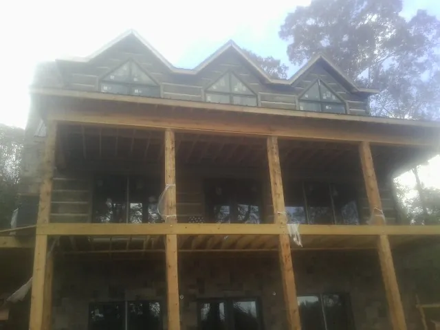 Dormers and porch framing on a large log home under construction — Roof Coating work by our crew in Pearlington