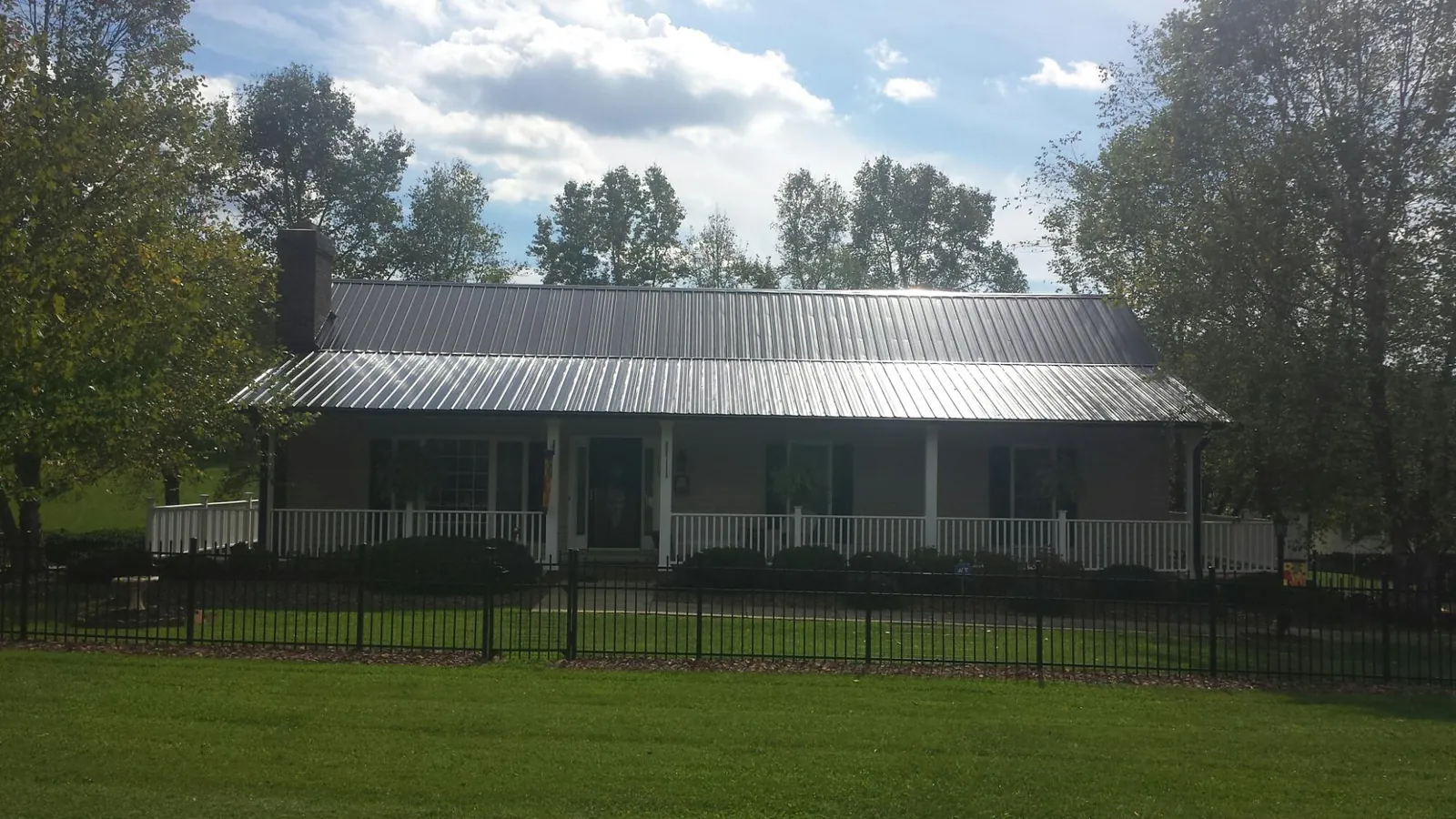Gray metal roof on a brick ranch with a full width front porch — Gutter Guard Installation work by our crew in Pearlington