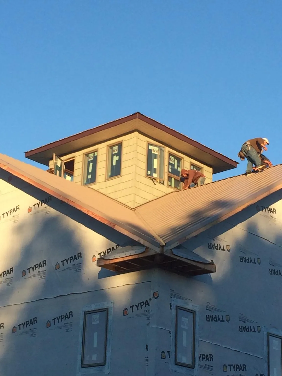 Roofers working around a rooftop cupola on a new metal roof at sunset — Roof Waterproofing in Pearlington by Roofing Brothers